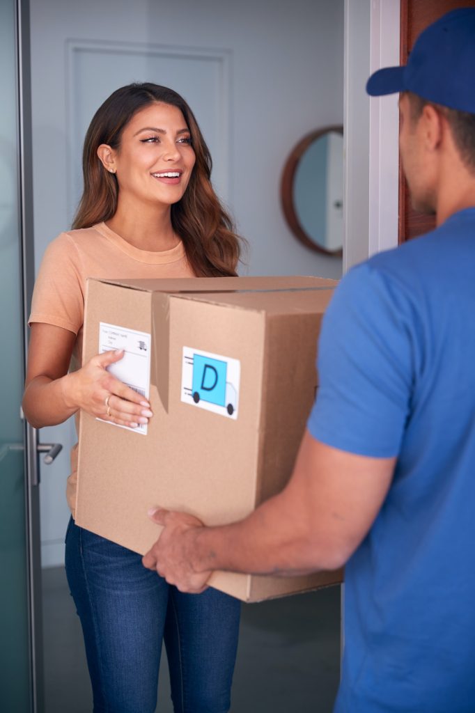 Woman Receiving Package Delivered By Courier To Home